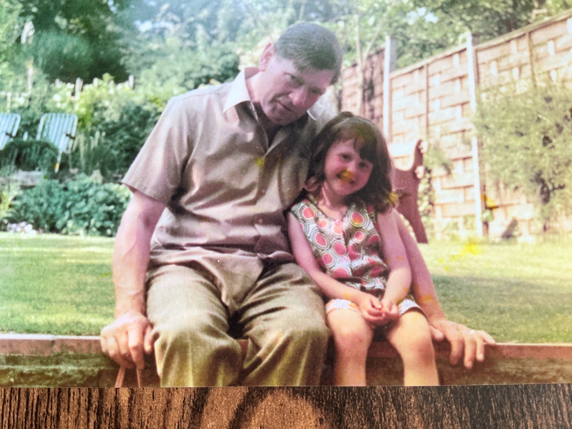 A father and his young daughter sitting together in a garden